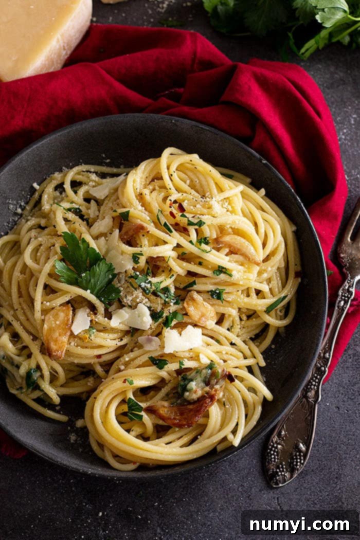 Garlic and Olive Oil Spaghetti 2 Top down view of spaghetti in a dark bowl and garnished with parmesan and parsley.