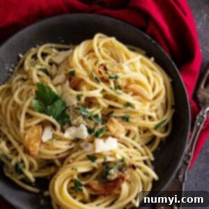 Garlic and Olive Oil Spaghetti 8 Top down view of spaghetti in a dark bowl and garnished with parmesan and parsley.