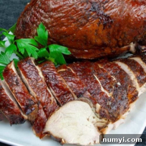 Smoked turkey breast on a white platter garnished with parsley.