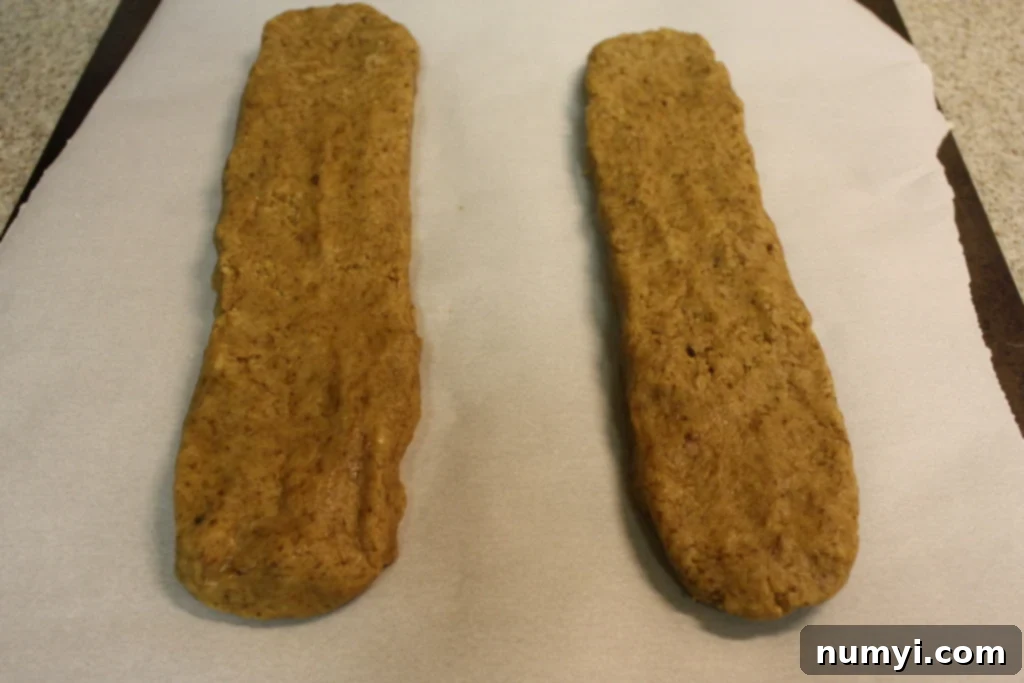 Espresso biscotti dough shaped into logs on a parchment paper lined baking sheet.