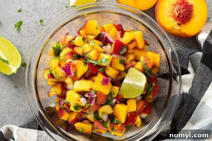 Top down view of peach salsa in a bowl garnished with fresh lime and cilantro. 