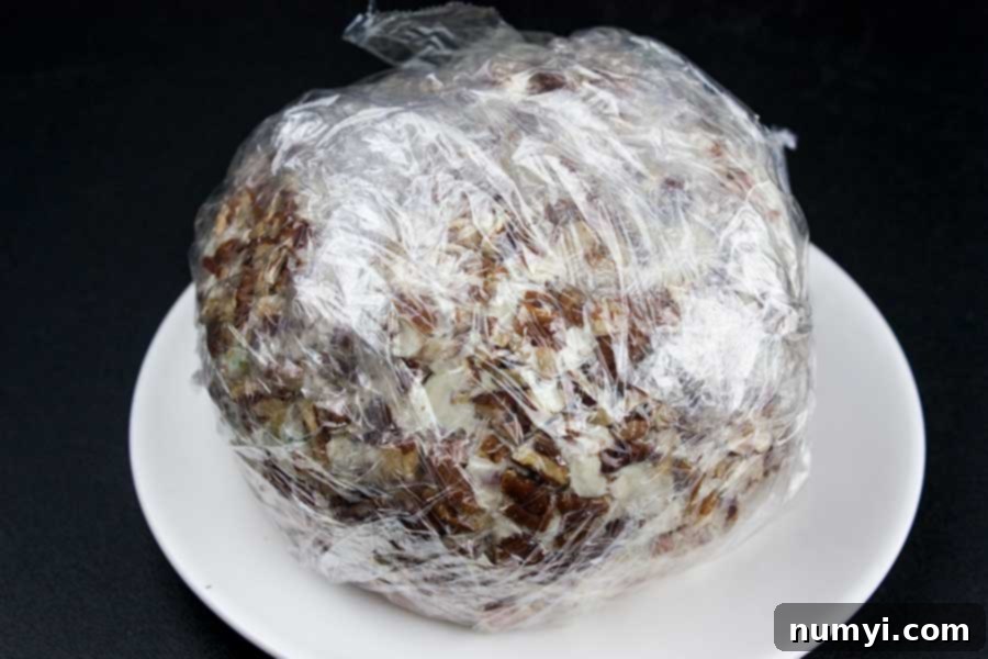 Pecan Crusted Cheese Ball Perfection 5 A tightly wrapped pecan-crusted cheese ball, perfectly formed and ready for chilling, promising rich flavors to come.