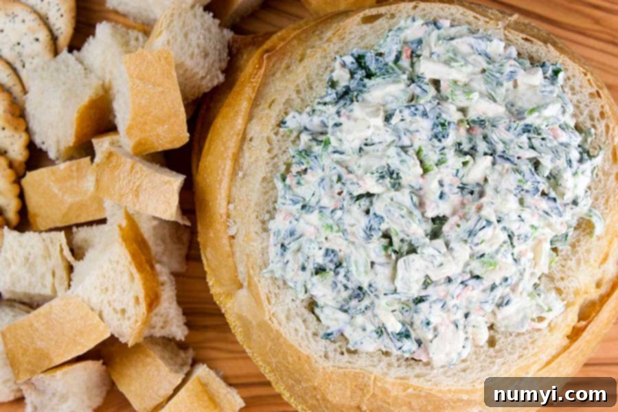 Easy Spinach Dip inside a bread bowl with cubed bread next to it, ready for serving.