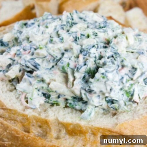Easy spinach dip in a bread bowl surrounded by bread cubes.