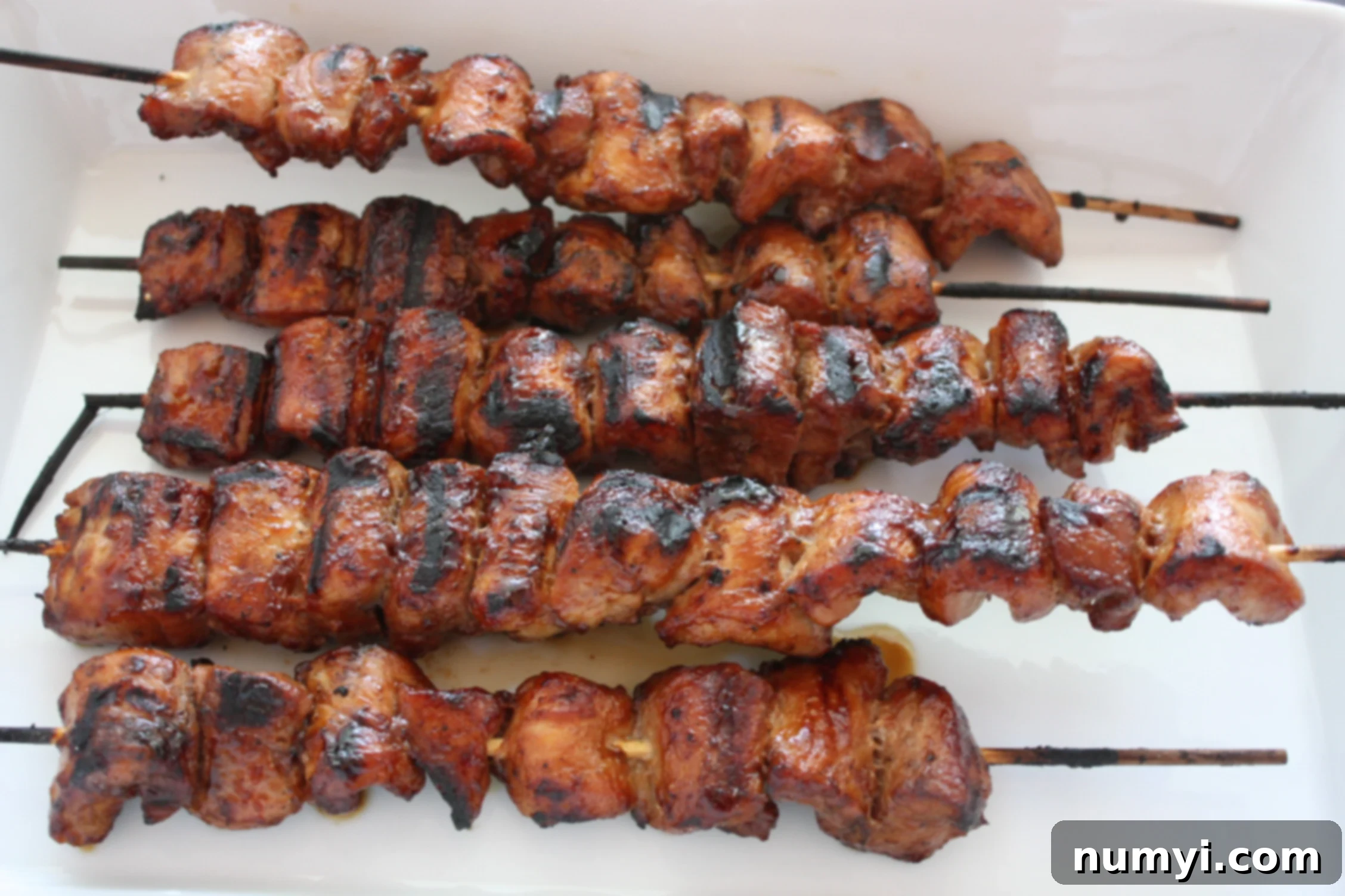 Classic Filipino Pork BBQ Skewers 3 Filipino Pork Kebabs (Pinoy) skewers on a white plate.