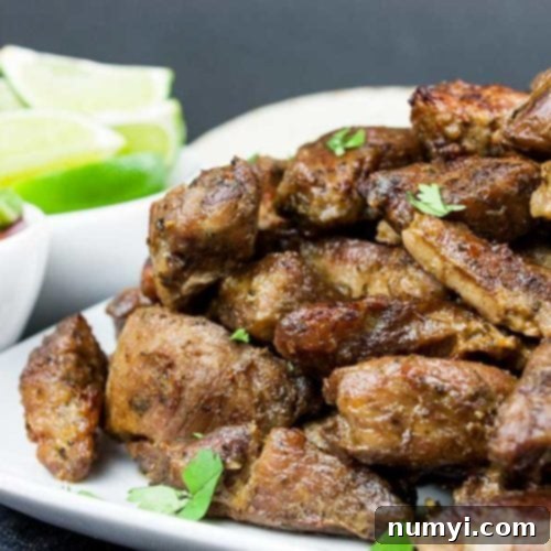 Crispy pork carnitas on a white platter garnished with chopped cilantro.