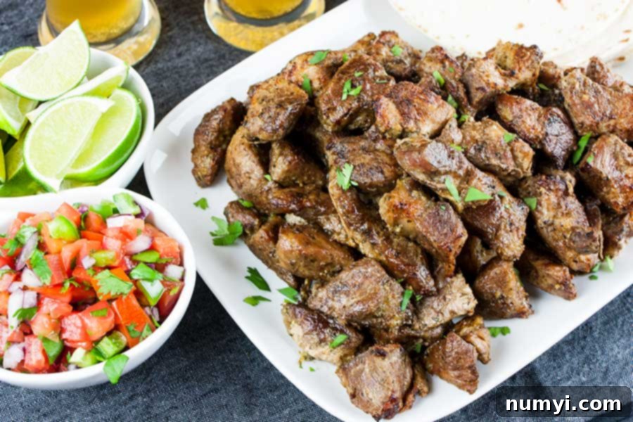Close-up of crispy pork carnitas on a white platter garnished with fresh chopped cilantro.