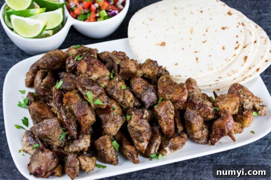 Platter of crispy pork carnitas with corn tortillas, lime wedges, and pico de gallo, ready for serving.
