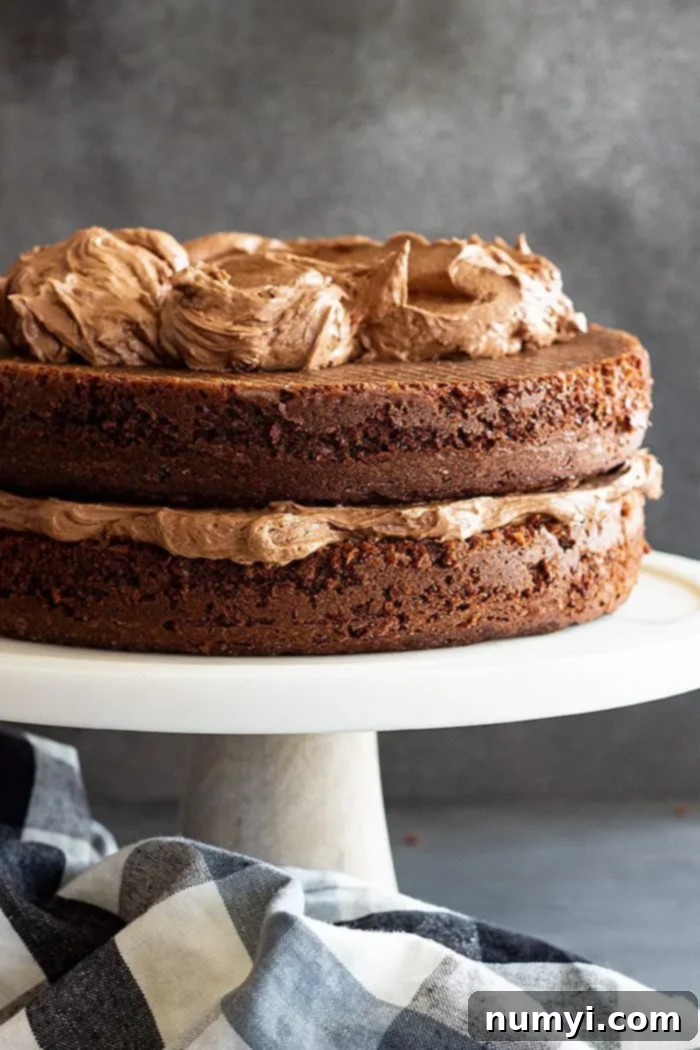 frosting devils food cake on white cake pedestal, showing smooth chocolate frosting