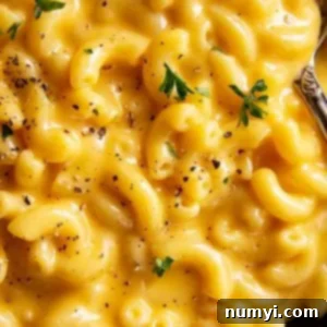 A close up of ultra creamy and cheese mac and cheese sprinkled with black pepper and a little parsley.