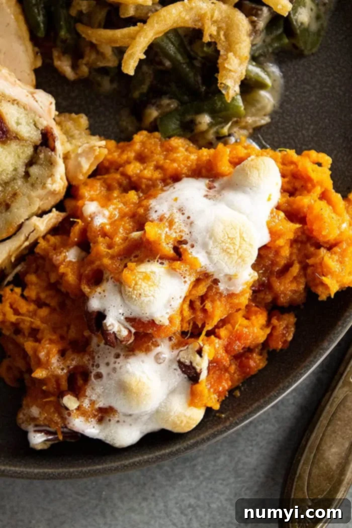 closeup: a generous portion of classic sweet potato casserole with marshmallows on a black plate