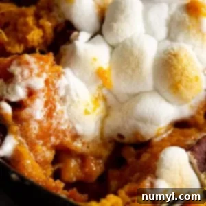 A close up of a scoop of sweet potato casserole take out and you can see the melty marshmallows.