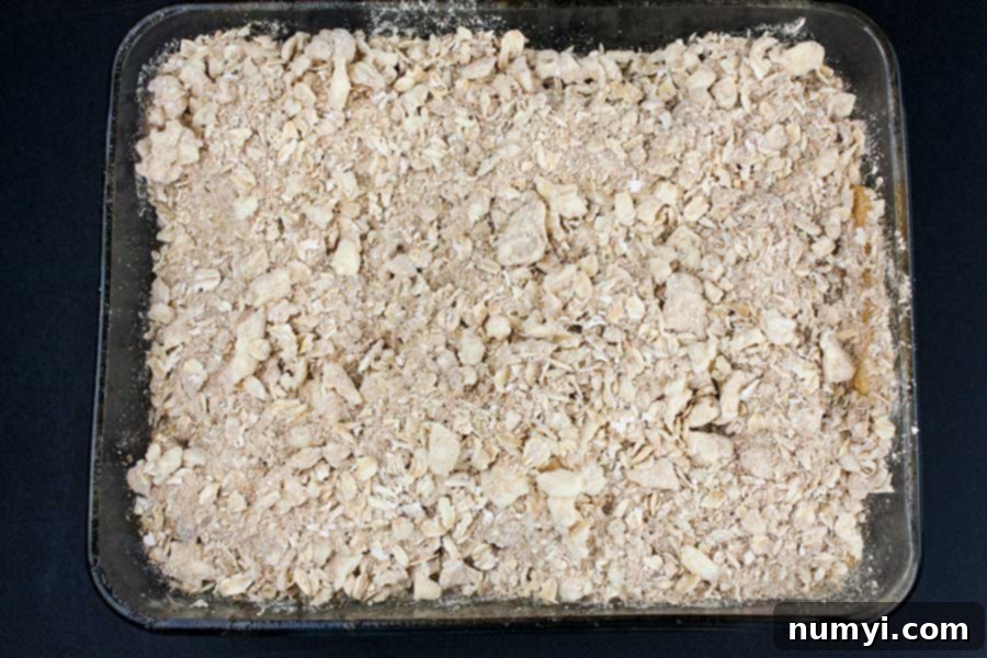 Comforting Apple Crisp with a Golden Oat Crumble 5 Apples and topping in a glass baking dish.