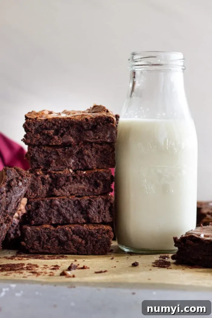 A tall stack of fudgy brownies next to a tall glass of cold milk. 