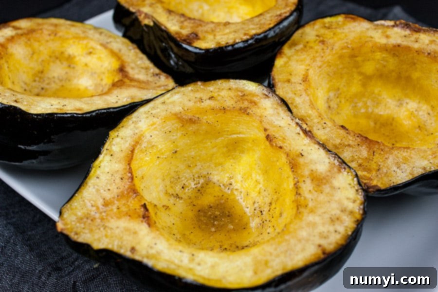 Roasted acorn squash halves on a white platter, beautifully browned and tender.