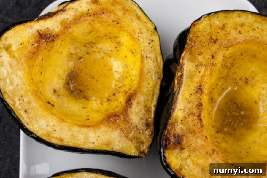 Closeup of a single roasted acorn squash half on a white plate, glistening and ready to eat.
