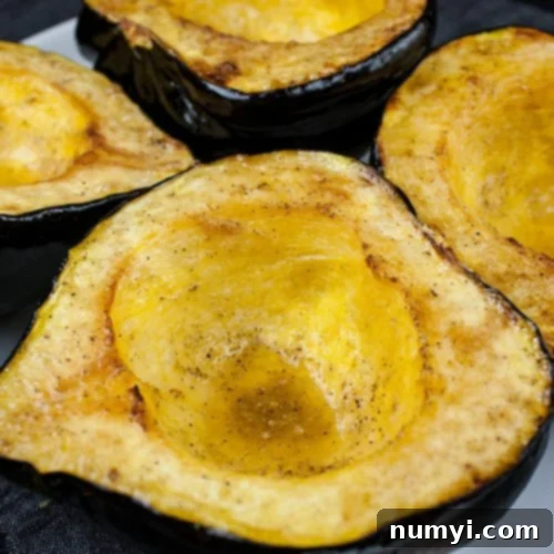 Roasted acorn squash halves on a white platter, beautifully browned and tender, ready to serve.
