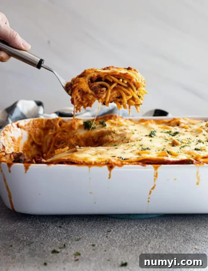 Million Dollar Baked Spaghetti 7 side view: pulling up a large portion of my million dollar spaghetti recipe from the casserole dish ready to serve