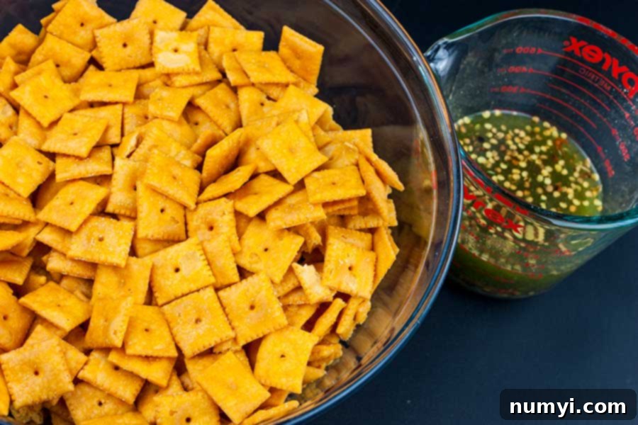 Exploding Cheese Bites 3 Firecracker Cheez-Itz - crackers in a large glass bowl with seasoning mixture in a glass measuring cup next to it