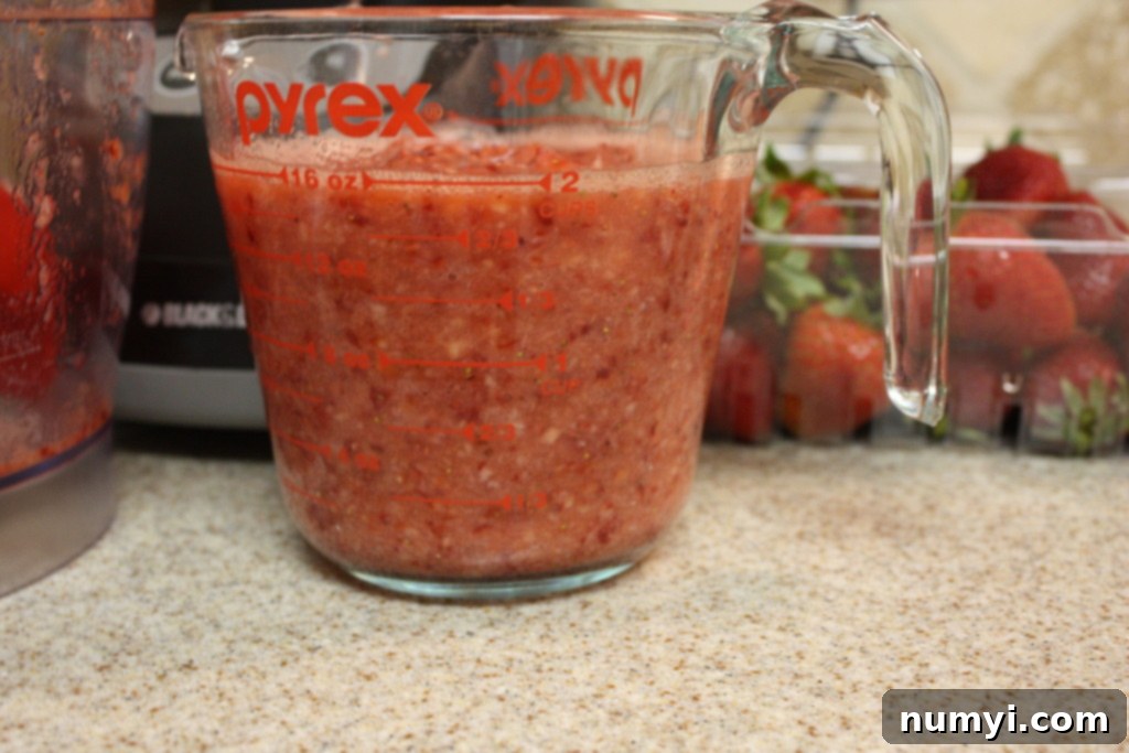 Fresh strawberry puree in a glass measuring cup.