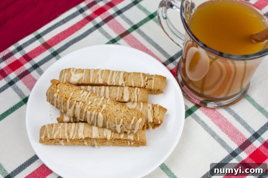 Spiced Apple Cider Biscotti on a white plate next to a glass mug of hot apple cider, ready to be dunked.