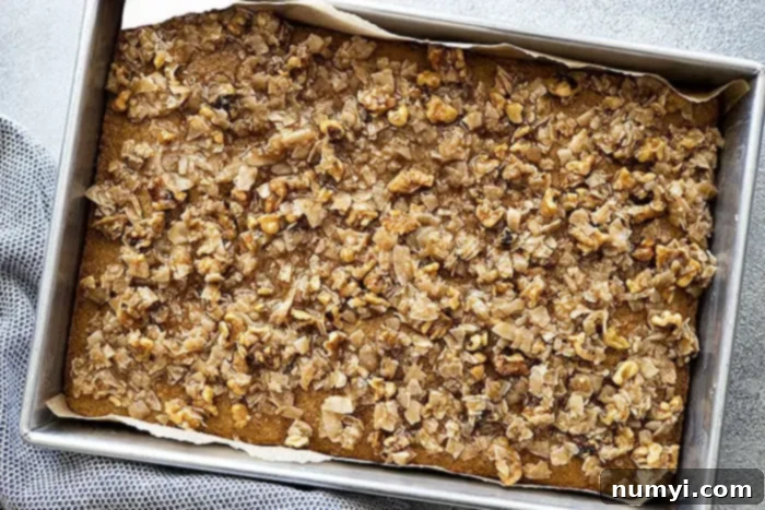 Hearty Spiced Oatmeal Cake 7 A close-up, overhead view of the Old Fashioned Oatmeal Cake with its luscious caramelized coconut and nut topping generously spread across the surface, poised to go under the broiler for its final golden touch.