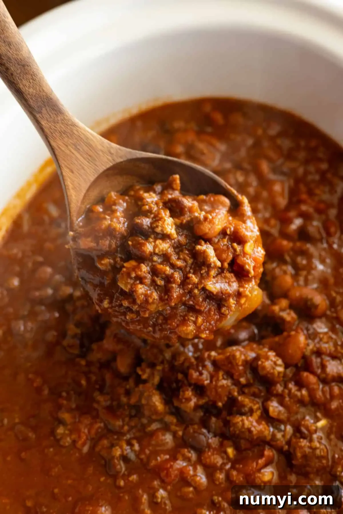 A ladle pulling up a ladle full of soup.