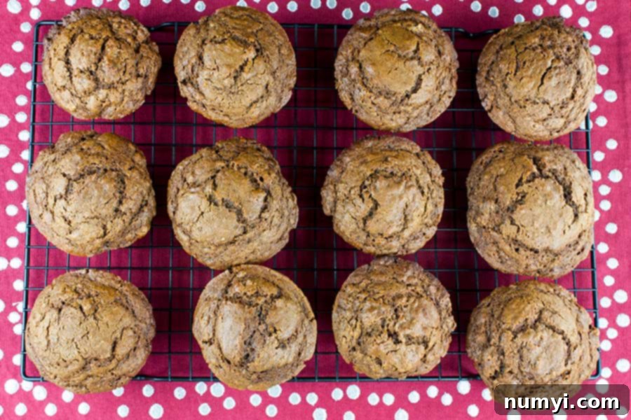 Spiced Molasses Muffins 3 Freshly baked gingerbread muffins cooling on a wire rack, showcasing their beautifully cracked tops.