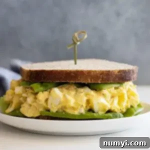 Irresistible Egg Salad 7 A beautifully crafted egg salad sandwich, showcasing its creamy filling and fresh lettuce, on a plate, ready to be enjoyed.
