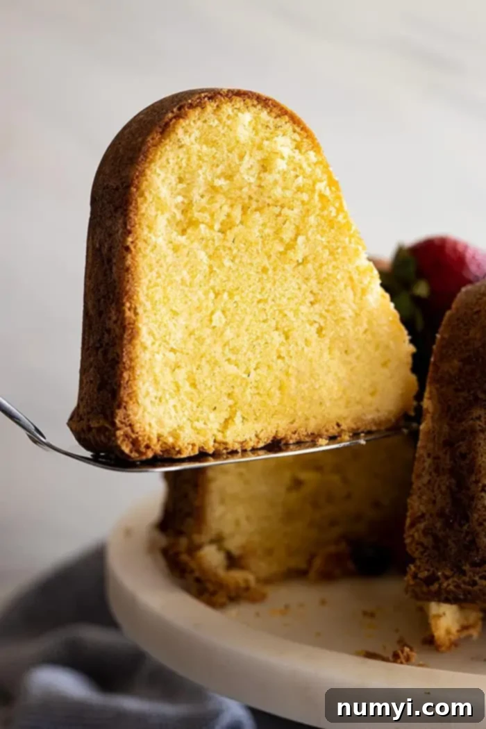 The Quintessential Pound Cake 5 A beautiful slice of dense, moist, vanilla pound cake being cut from the larger cake, ready for serving.