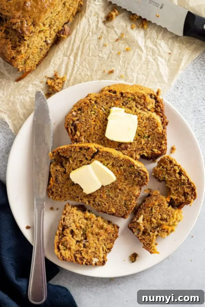 Wholesome Zucchini Carrot Loaf 2 overhead: slices of zucchini carrot bread on a plate topped with pats of butter with a knife and a napkin off to the side