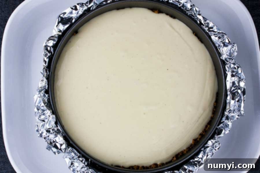 Unbaked eggnog cheesecake batter in springform pan placed in water bath, showing the smooth, creamy consistency before baking.
