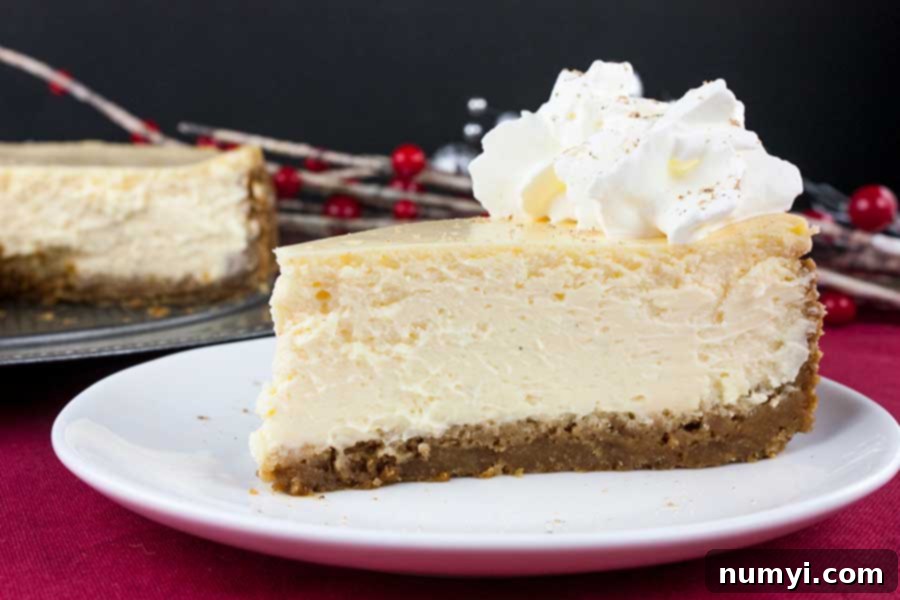 A beautifully presented slice of eggnog cheesecake garnished with a swirl of whipped cream and a dusting of nutmeg.