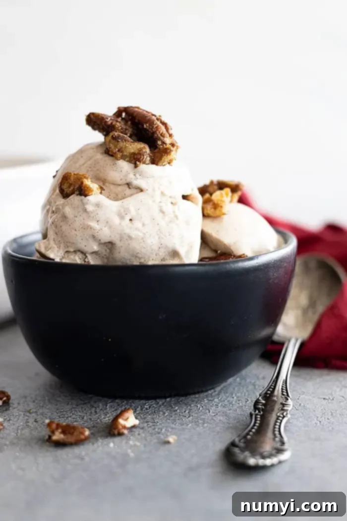 A bowl of creamy cinnamon ice cream topped with crunchy candied pecans, ready to be enjoyed.