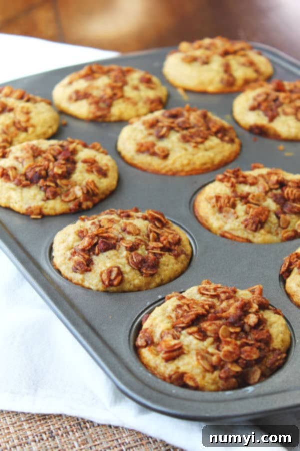 toasted oatmeal banana muffins in a muffin tin and covered in pecans