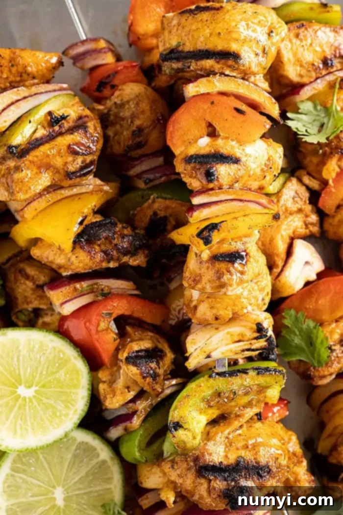 A close-up of beautifully grilled chicken fajita kebabs, artfully arranged and garnished with vibrant lime slices and fresh cilantro, ready to be served.
