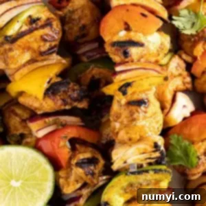 A close-up of a single grilled chicken fajita kebab, showing the beautiful char on the chicken and vegetables, with a fresh lime wedge.