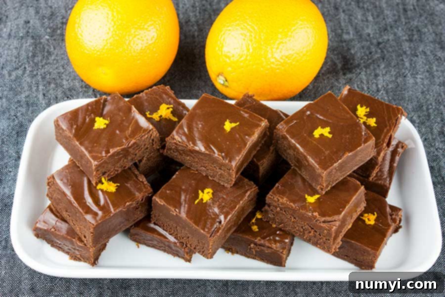 Chocolate Orange Fudge cut in squares placed on a white plate and garnished with orange zest.