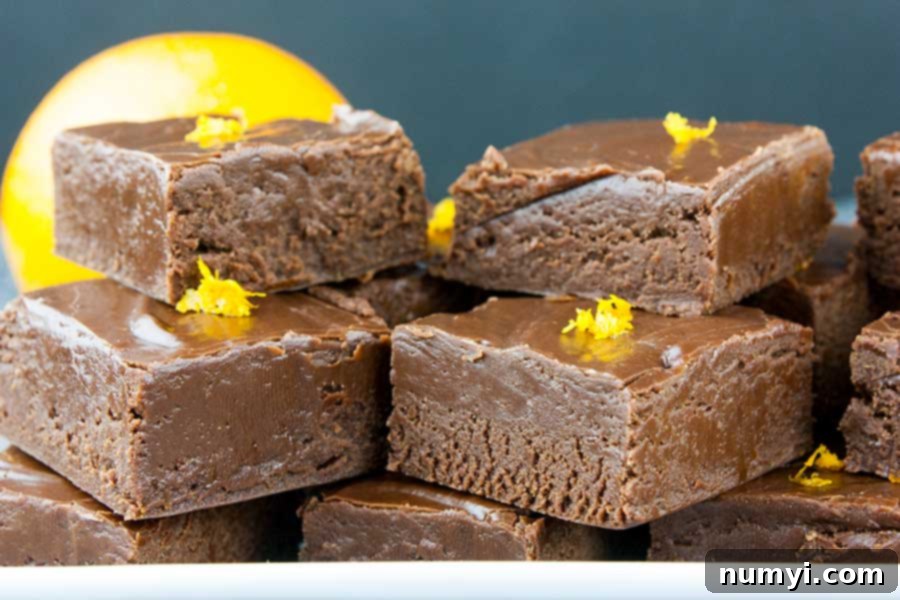 Closeup of fudge cut in squares placed on a white plate and garnished with orange zest.