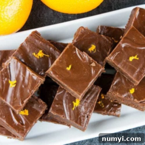 Chocolate orange fudge on a white rectangle platter garnished with orange zest.