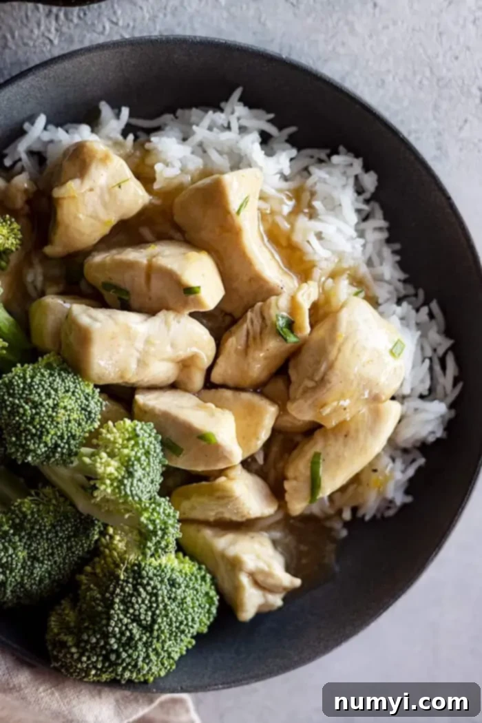 Overhead view of chinese lemon chicken in a bowl over white rice and a side of steamed broccoli.
