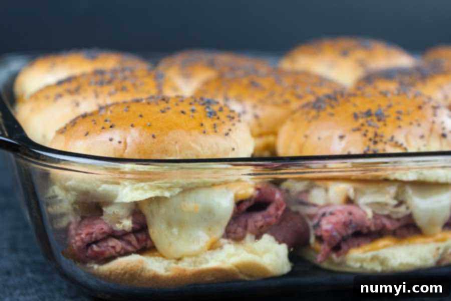 Freshly baked pastrami and swiss cheese sliders, with melted cheese and a golden crust, ready to serve.