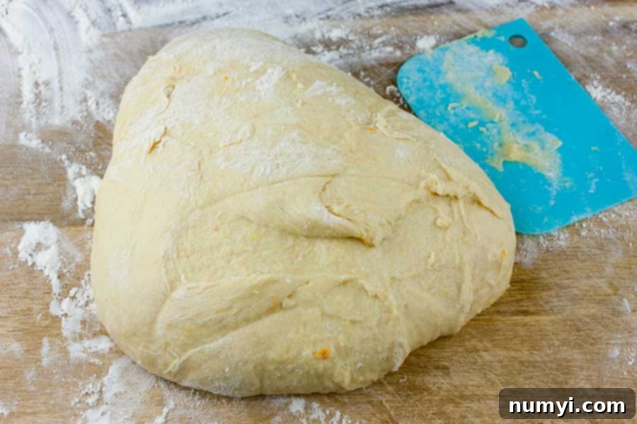 Simple Italian Christmas Panettone 8 Sticky panettone dough on a lightly floured wooden board, ready for gentle handling.