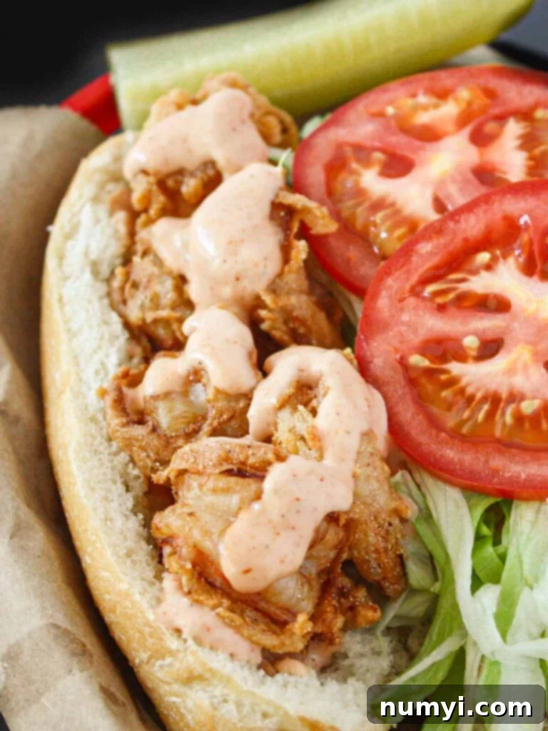 A perfectly assembled shrimp po'boy in a brown paper lined red basket, garnished with lemon.