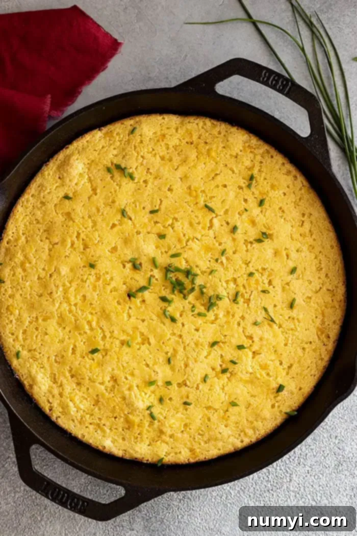 An overhead view of the freshly baked cornbread casserole, hot from the oven and garnished with finely chopped chives, ready to be served.