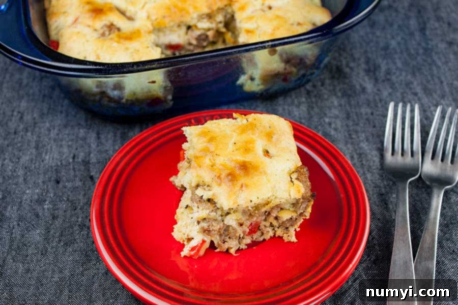 Hearty Sausage Breakfast Casserole 5 A perfectly baked slice of golden-brown sausage breakfast cake, revealing its cheesy, savory layers, served on a red plate.