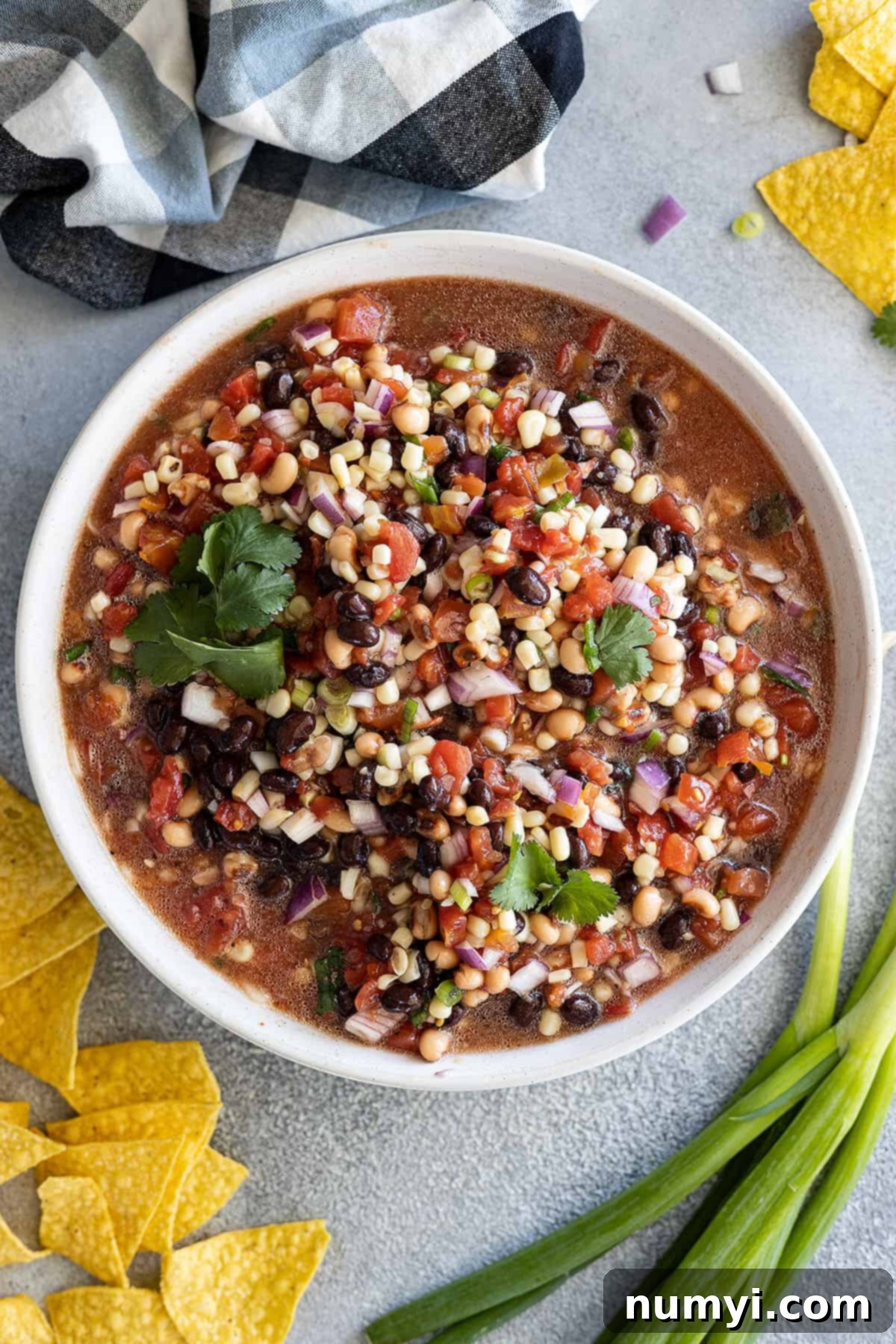 Overhead view of a large white bowl filled with colorful Cowboy Caviar dip, surrounded by tortilla chips.