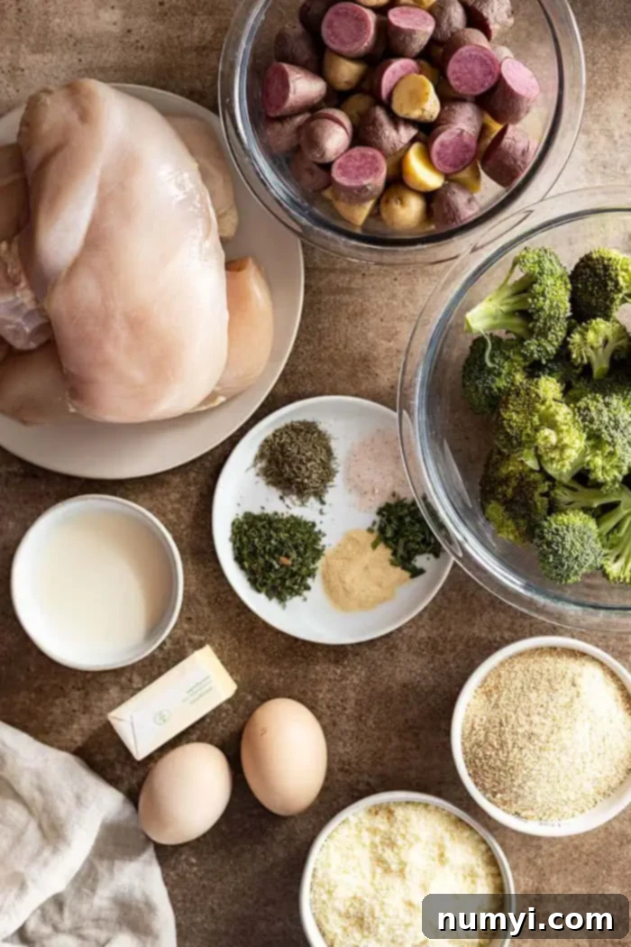 A flat lay photograph showing all the fresh ingredients needed for sheet pan parmesan crusted chicken and vegetables.
