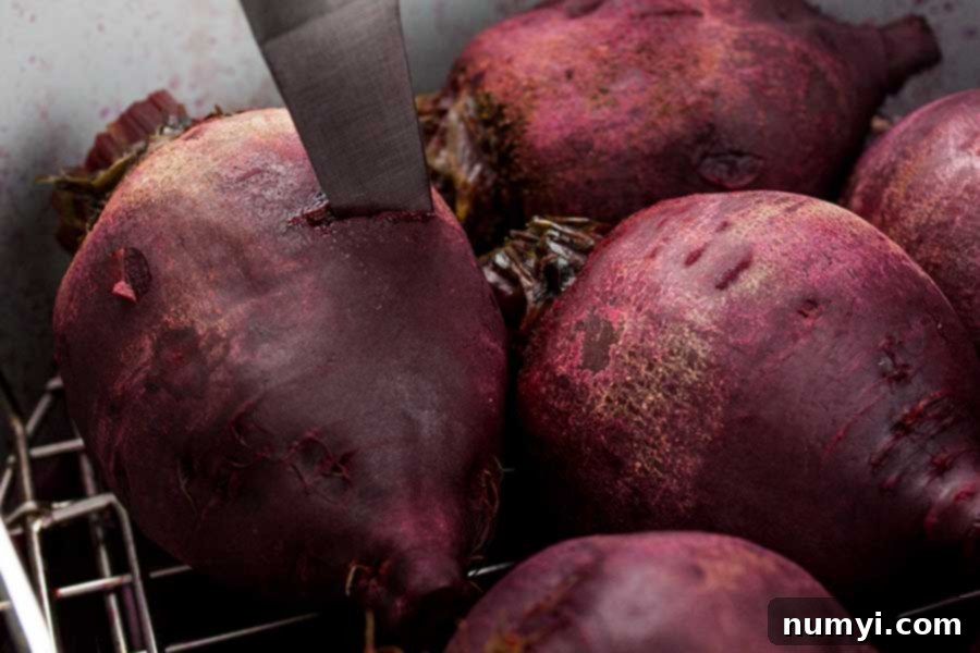 A sharp knife gently pierces a cooked beet, demonstrating its perfect tenderness after pressure cooking.