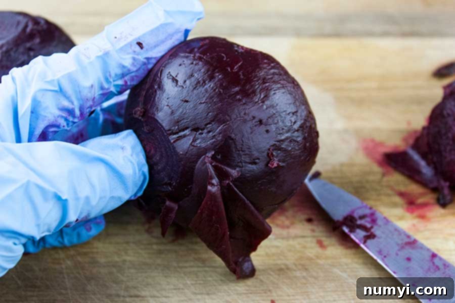 A gloved hand expertly removes the skin from a cooked beet using a small paring knife, highlighting the ease of peeling after pressure cooking.